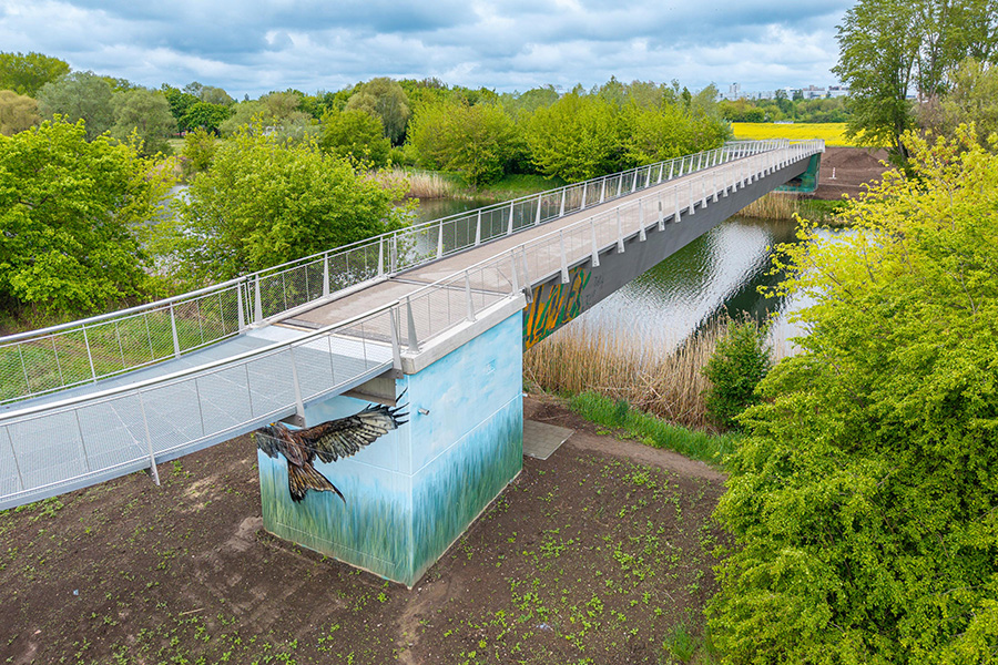 Fernwärmebrücke über den Ruderkanal mit Vogel-Graffiti unterhalb der Brücke.