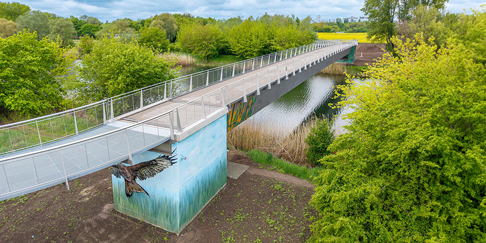 Fernwärmebrücke über den Ruderkanal mit Vogel-Graffiti unterhalb der Brücke.