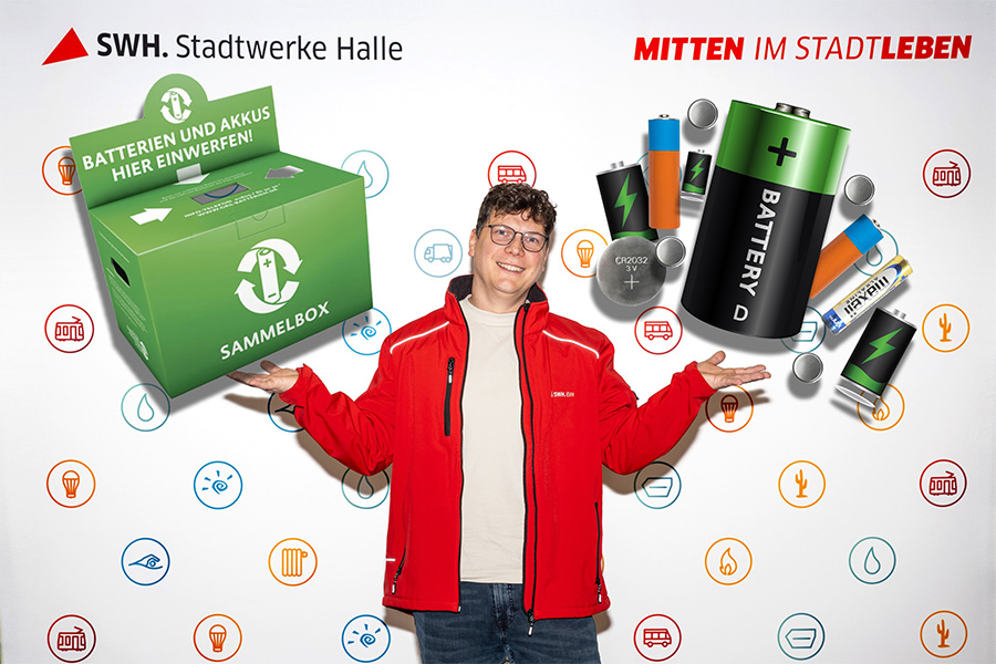 Mitarbeiter balanciert fotomontierte Batterien und eine Batteriesammelbox auf den Händen.
