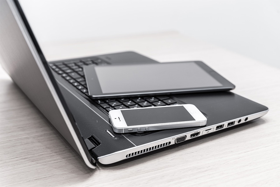 Ein Handy und ein Tablet liegen auf einem aufgeklapptem Laptop.