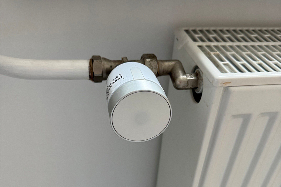 Nahaufnahme eines weißen Thermostatventils an einem Heizkörper.