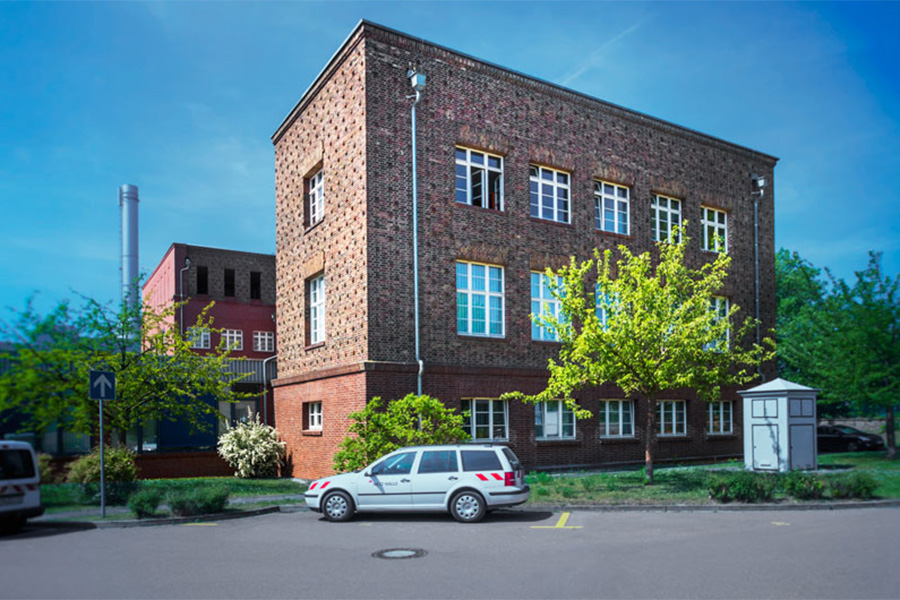 Backsteingebäude, davor parkt ein PKW.