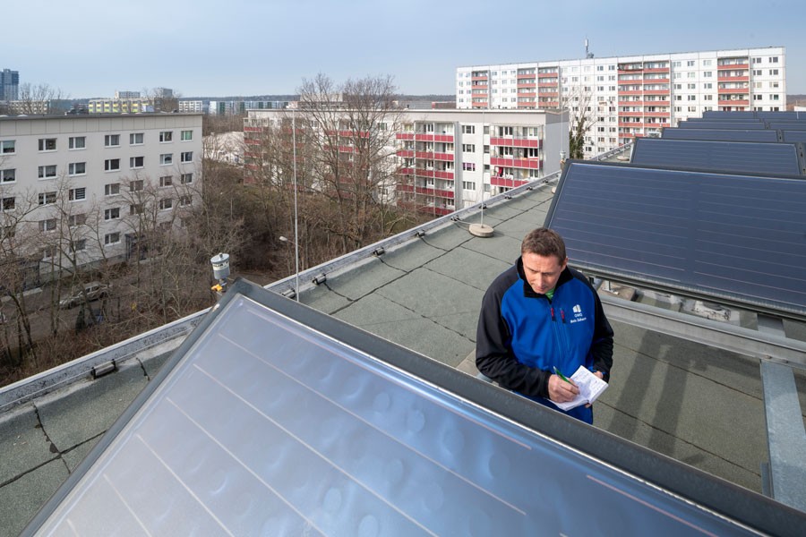 Mann steht auf Dach mit Solarthermie