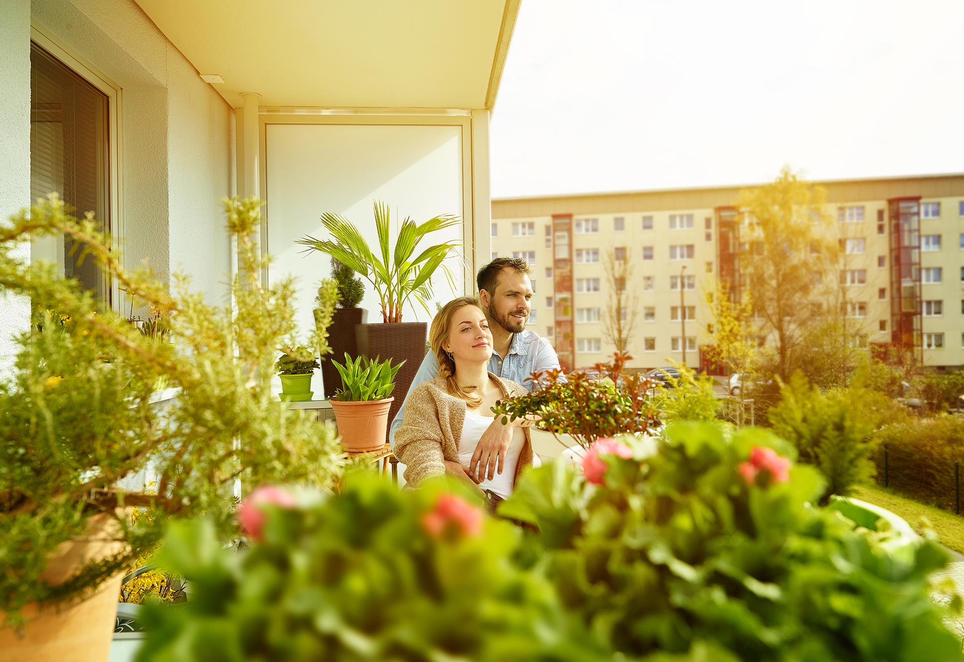 Mann und Frau sitzen auf einem Balkon mit Blumen.