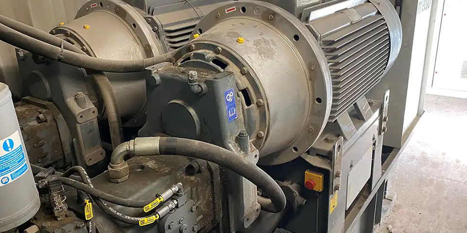 Großaufnahme einer technischen Heizungsanlage mit Motor, Pumpen und angeschlossenen Leitungen.