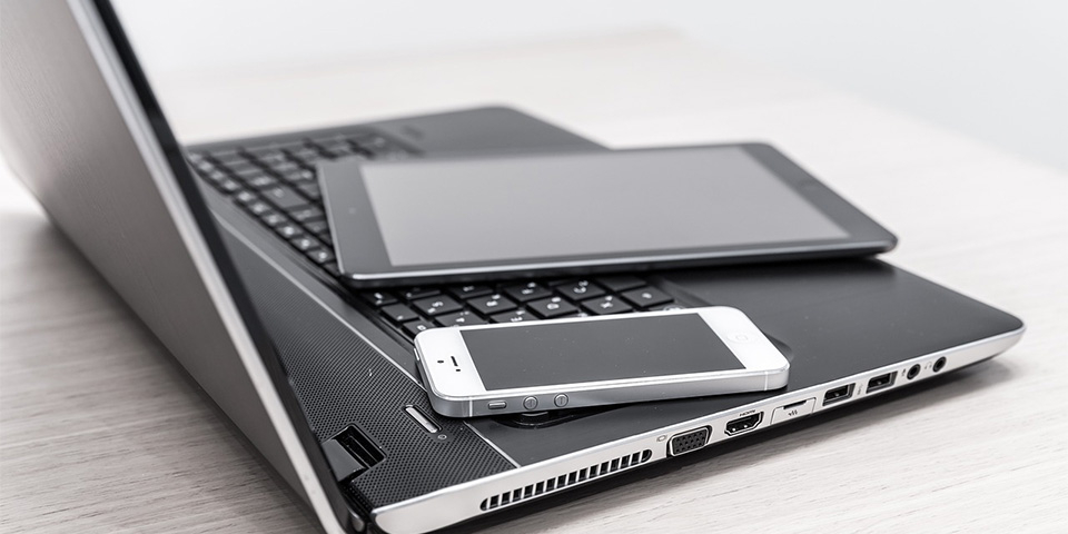 Ein Handy und ein Tablet liegen auf einem aufgeklapptem Laptop.