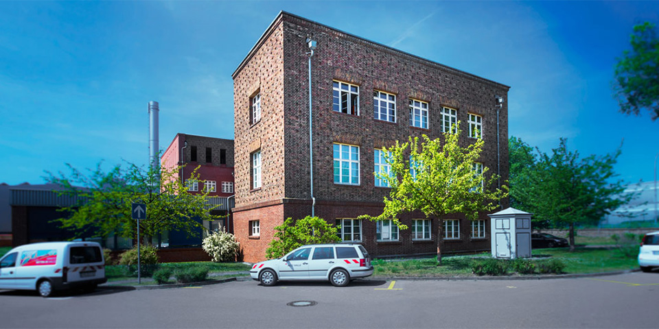 Backsteingebäude, davor parkt ein PKW.
