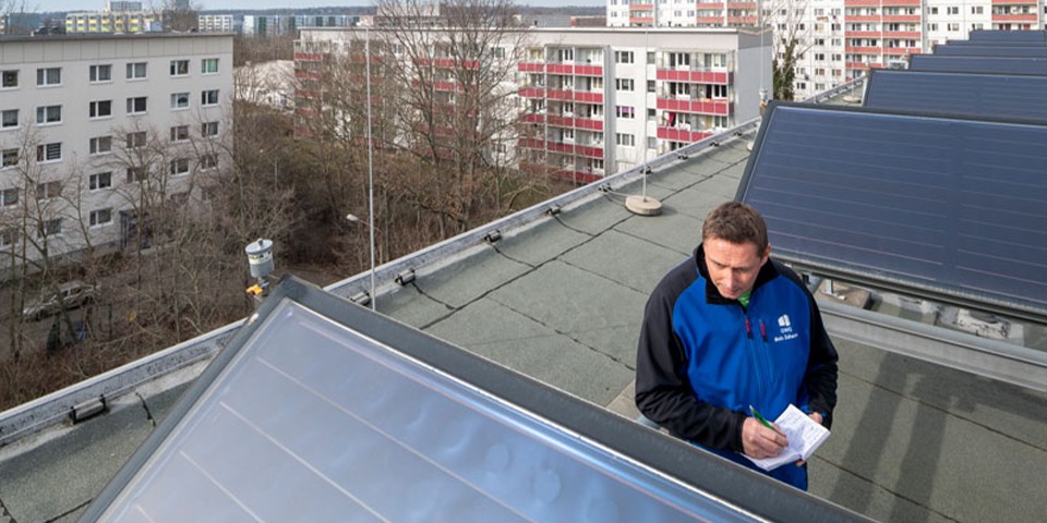 Mann steht auf Dach mit Solarthermie.