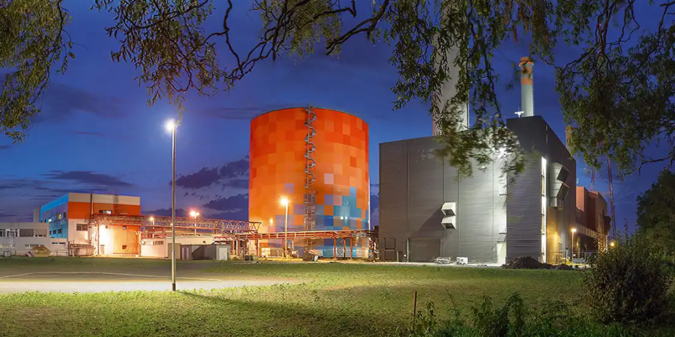 Wärmespeicher und Kraftwerksgebäude bei Nacht.